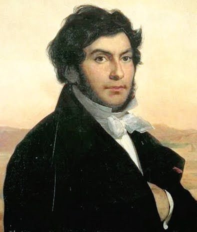Painted portrait of Jean-François Champollion with dark curly hair and side whiskers, in a dark coat and white cravat, in front of an Egyptian landscape