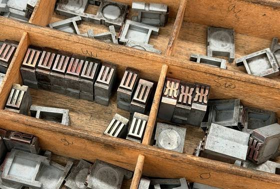 Metal printing type sorted into the wooden compartments of a printer's type case